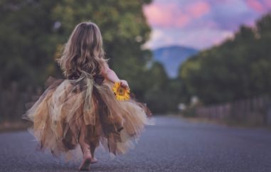Little girl skipping with a flower in her hand.